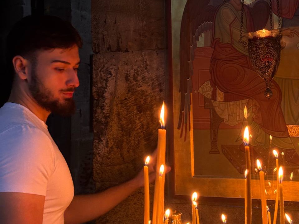 Luka zündet in einer Kirche Kerzen vor einer Ikone an