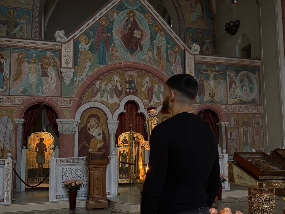 Ein Mann steht betend vor der bemalten Ikonenwand einer orthodoxen Kirche